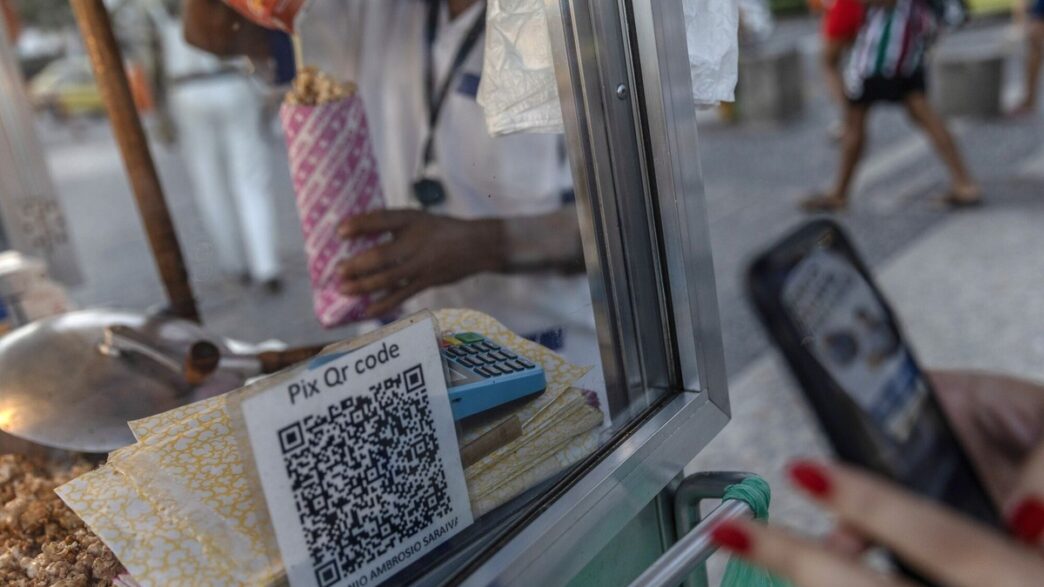 Pessoas usando smartphones para pagamentos em lojas físicas, indicando a consolidação do celular como meio de transação.