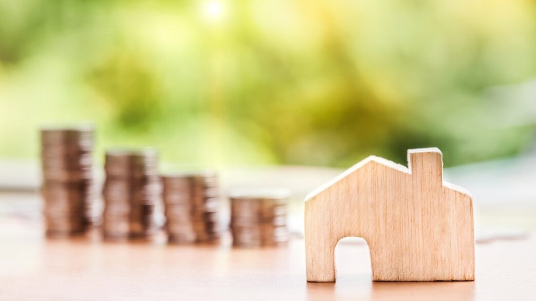 Casa com símbolo de dinheiro em frente, representando o mercado imobiliário e o custo de moradia. Estudo do BC sobre crédito imobiliário.