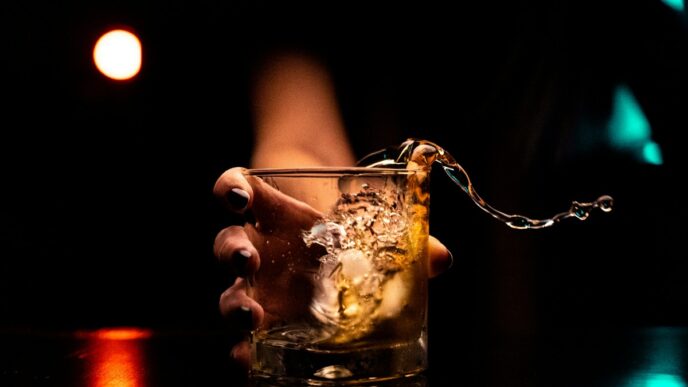 Homem bebe em um copo com gelo em um bar, refletindo o tema do medo de beber após adulteração por metanol.