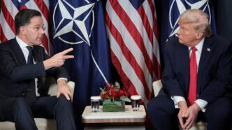 Bandeira dos Estados Unidos ao lado do emblema da Otan.