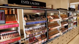 Logotipos da Estée Lauder e Puig representando a fusão das empresas.