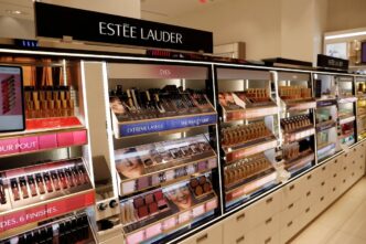 Logotipos da Estée Lauder e Puig representando a fusão das empresas.