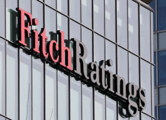 Logotipo da agência Fitch Ratings sobre gráfico de indicadores econômicos dos EUA.