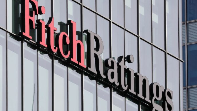 Logotipo da agência Fitch Ratings sobre gráfico de indicadores econômicos dos EUA.
