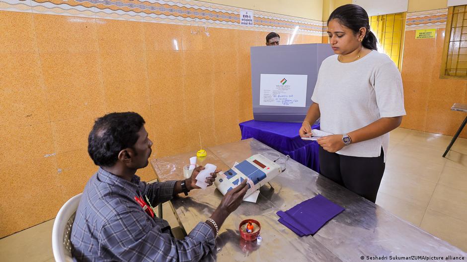 Eleitores indianos aguardam em fila para votar em seção eleitoral.